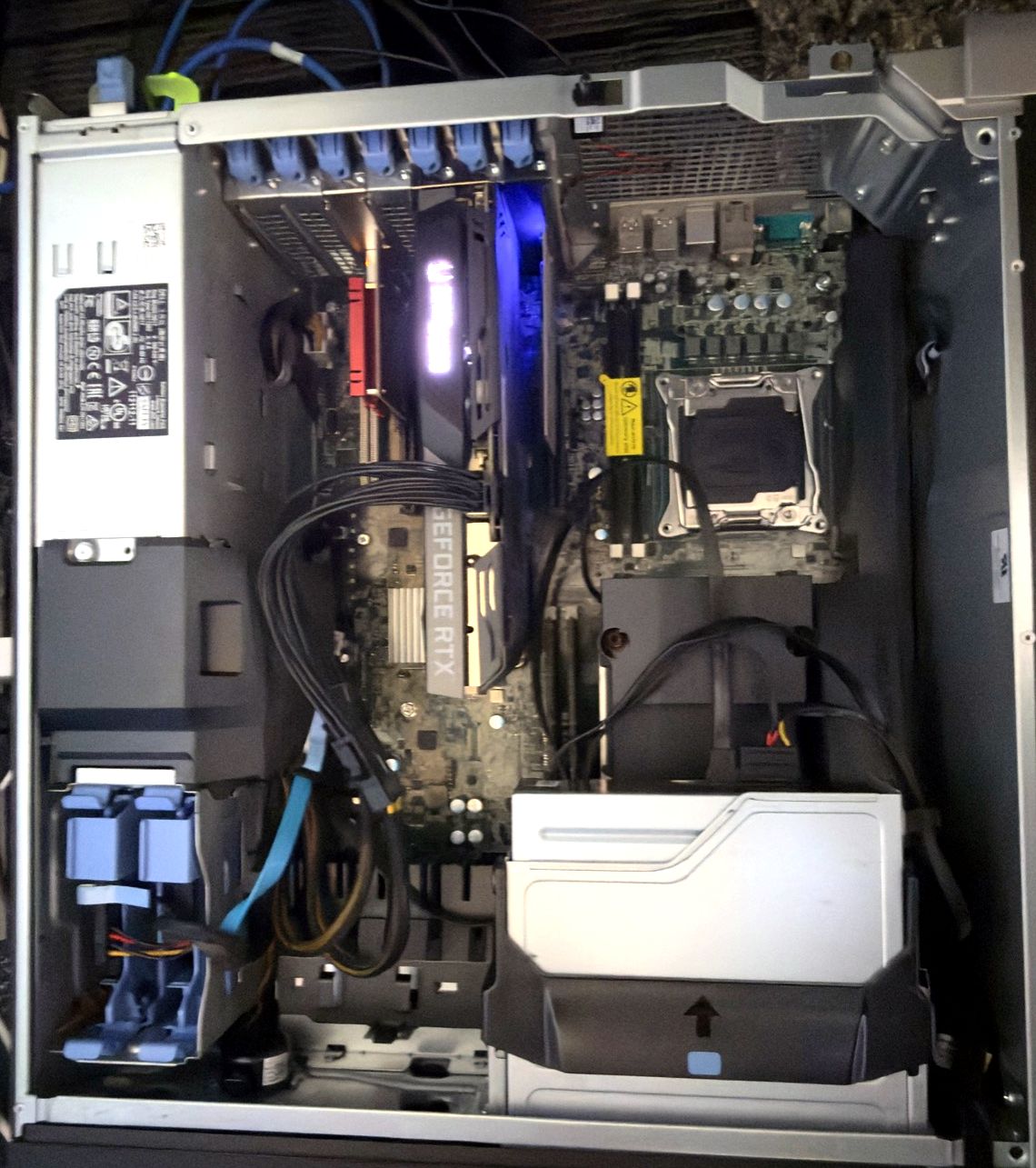 The open Dell Precision 7810 from above: power supply top left, an RTX 3060 Ti and a red low-profile card in the PCIe slots, an empty CPU socket at the right, drive cages below.